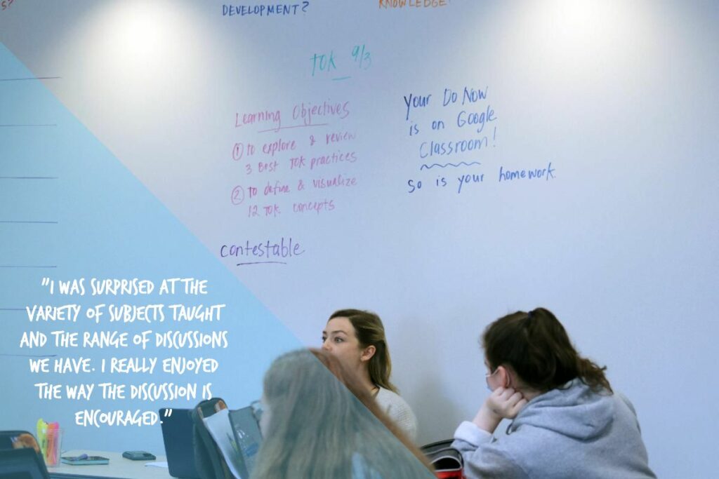 Image of IB Core TOK classroom with teacher and two students. Image includes quote from student, "I was surprised at the variety of subjects taught and the range of discussions we have. I really enjoyed the way the discussion is encouraged."